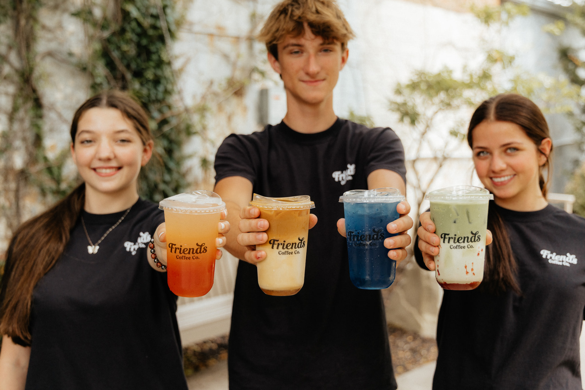 Team members holding four specialty drinks